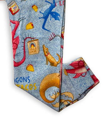 Pajama pants detail showing dragons, tacos, and Taco Cave bag illustration