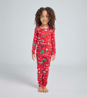 Child wearing red Christmas pajama set with festive holiday illustrations