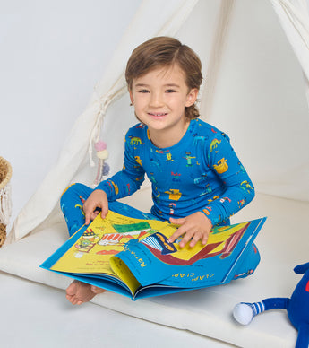 Child wearing blue Pete the Cat pajamas, reading a book