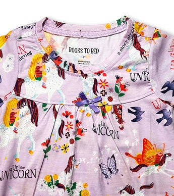 Close-up of Uni the Unicorn nightdress neckline with purple bow and storybook characters