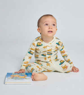 Toddler wearing Biscuit puppy print coverall, holding a book
