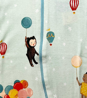 Close-up of coverall fabric featuring illustrated children, balloons, and stars