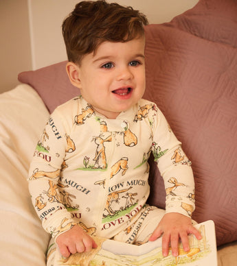 Smiling baby in bunny print coverall with "Guess How Much I Love You" book